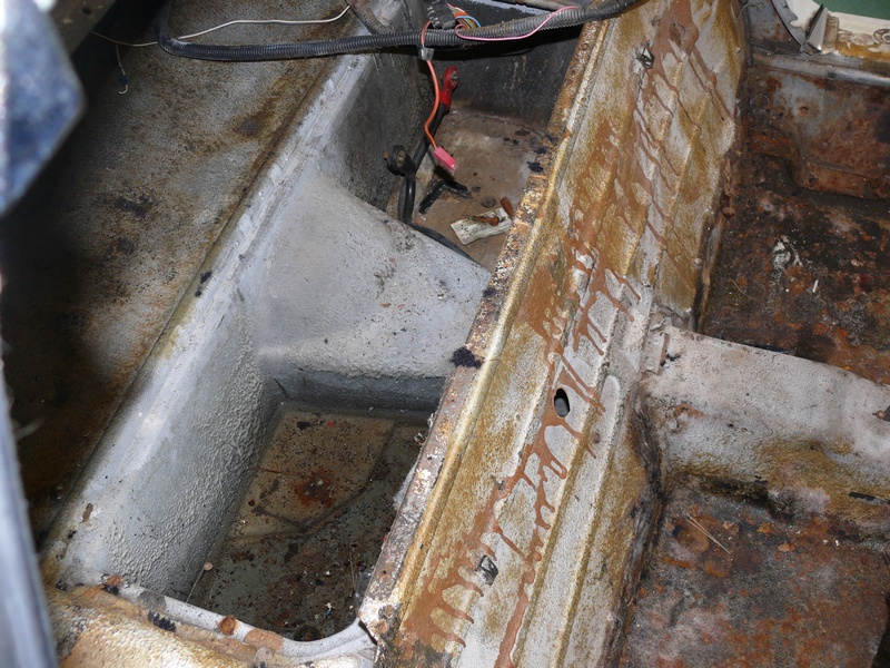 Rusted interior floor pan with wiring visible