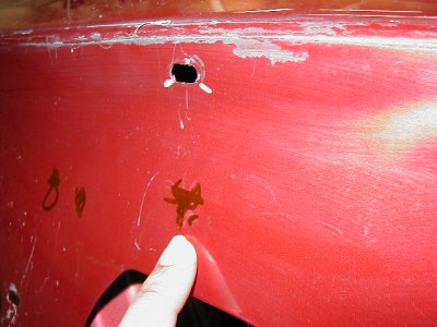 1997 Ford Taurus - Close-up of a red car's body panel showing a hole and some rust marks.