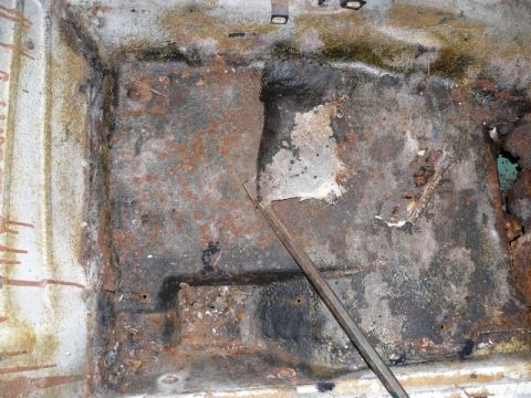 1976 Chevrolet Corvette - The interior floor pan shows extensive rust and corrosion, indicating significant damage and potential structural compromise.
