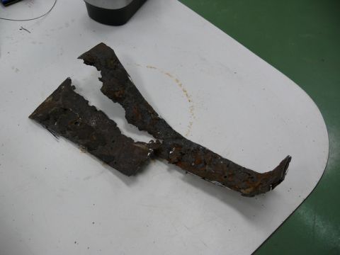 1976 Chevrolet Corvette - Severely rusted metal fragments, likely from a vehicle's undercarriage, are displayed on a white surface. The Supermotors.net logo is visib…