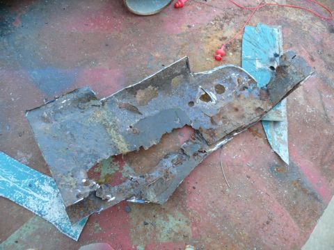 1976 Chevrolet Corvette - Fragment of rusted metal, possibly from a car body, lies on a painted surface.