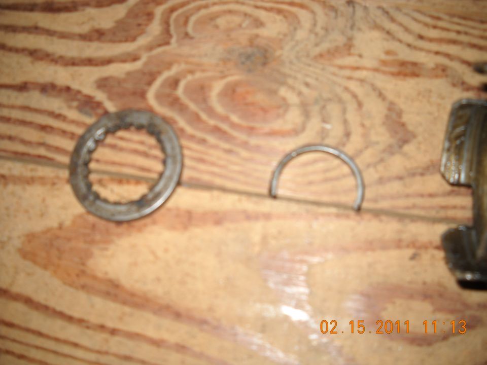 Two metal bearing rings and a partial metal piece on a wooden surface. Date stamp 02/15/2011