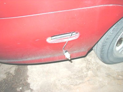 1997 Ford Taurus - Close-up of a red car's side panel showing an exposed light fixture with wiring, suggesting a modification or repair in progress.