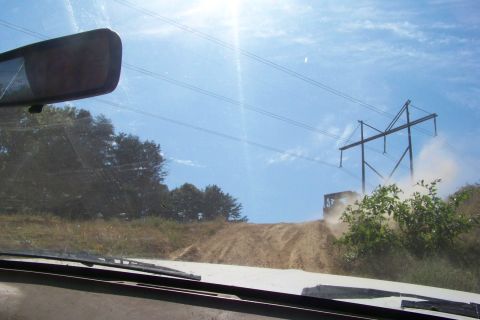 1989 Ford Bronco - An off-road vehicle navigates a dusty hill climb beneath a towering electrical pylon.