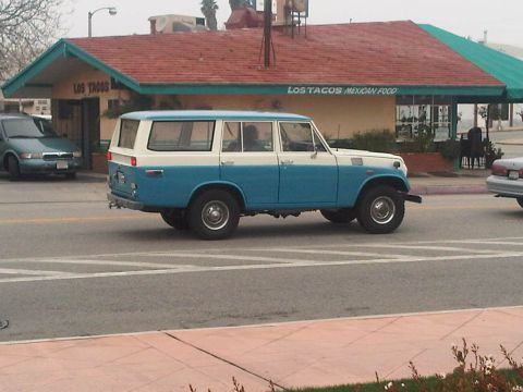 1986 Ford Bronco - This vintage SUV, likely from the 1970s, is seen driving on a street in front of a Mexican food establishment.