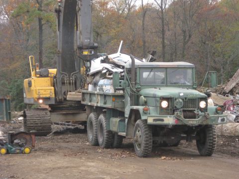 1985 Chevrolet Blazer - Military truck and excavator at a scrap yard, with a load of debris in the truck bed.