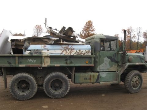 1985 Chevrolet Blazer - A military cargo truck is seen from the side, carrying a load of mangled scrap metal and debris.