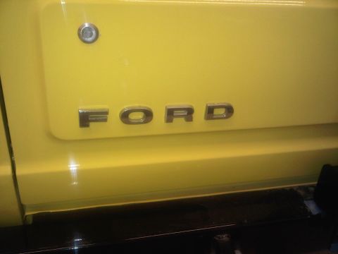 1978 Ford Bronco - The 'FORD' emblem is visible on the side of a yellow vehicle.