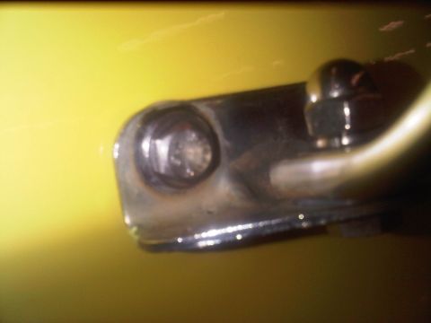 1978 Ford Bronco - Close-up of a chrome trim piece on a yellow vehicle, showing a bolt and a pipe.
