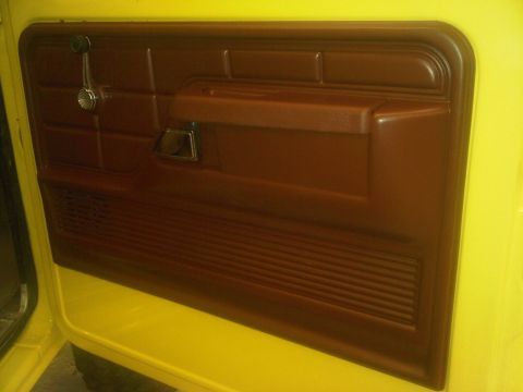 1978 Ford Bronco - Close-up of a vehicle's interior door panel, showing brown trim and a yellow exterior.