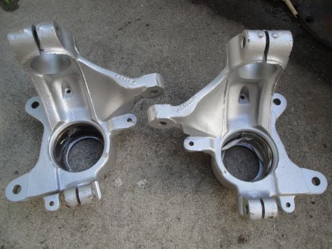 1993 Ford Taurus - Two silver painted steering knuckles are shown resting on a concrete surface.