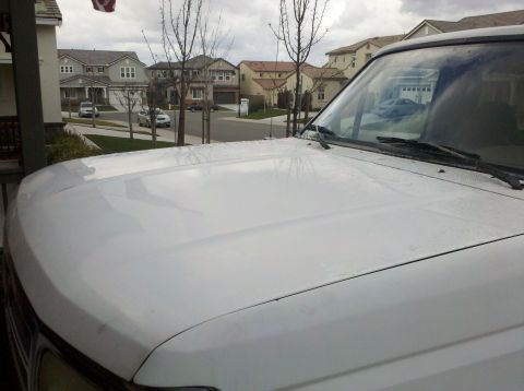 1995 Ford Bronco - White SUV hood and windshield with water spots, taken from a low front angle.