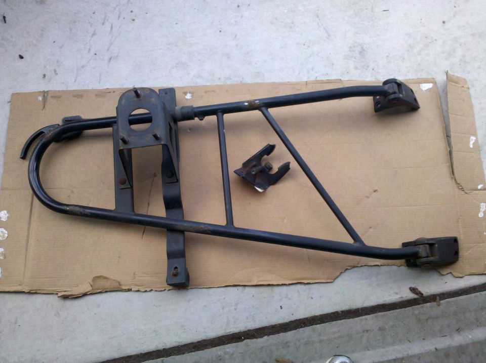 Black swing-out spare tire carrier frame with hinges and latch bracket laid on cardboard