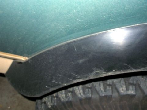 1990 Ford Bronco - Close-up of a green fender flare and tire tread, part of a vehicle.