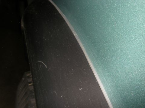 1990 Ford Bronco - Detail of a vehicle's fender flare and tire, with a green body panel visible.