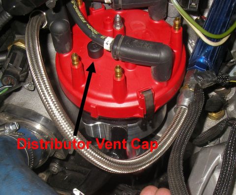 1990 Ford Bronco - Close-up of a red distributor cap with brass spark plug terminals, marked with a black arrow and red text labeling the 'Distributor Vent Ca…