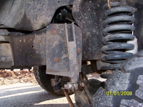 1989 Ford Bronco - Detail of a vehicle's suspension system, showing a rusty bracket and coil spring.