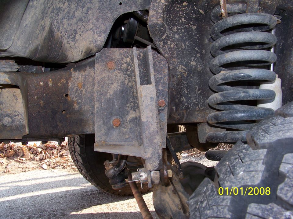 Close-up of rusty suspension bracket and coil spring on a vehicle's undercarriage