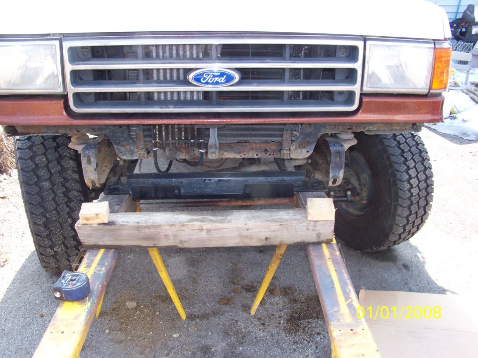 Front of a Ford truck on jack stands, showing the grille and headlights