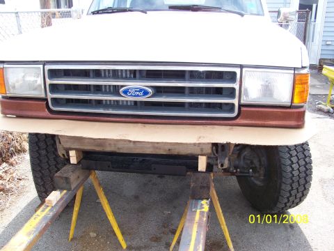 1989 Ford Bronco - Front view of a Ford Bronco, supported by sawhorses, showing the grille and bumper area.