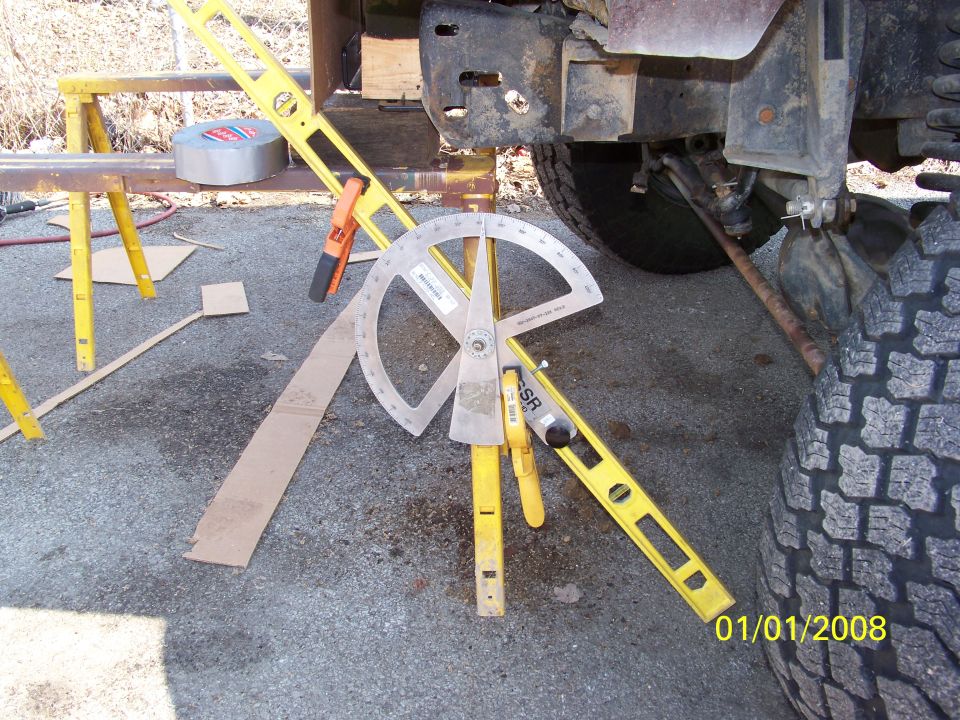 Protractor angle finder and level set against lifted 4x4 front axle to measure pinion angle