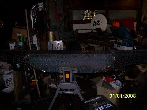 1989 Ford Bronco - A custom diamond plate bumper is displayed in a cluttered garage setting.