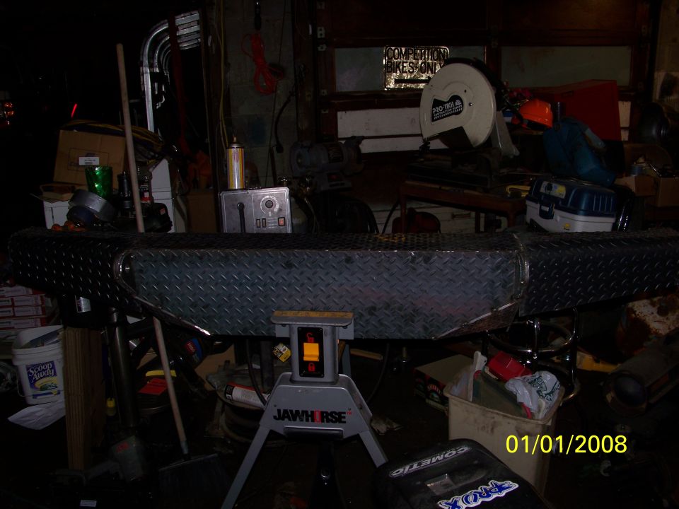 Diamond plate bumper on a stand in a workshop, with tools and boxes in the background