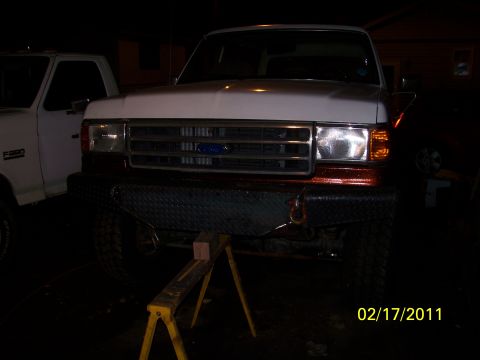 1989 Ford Bronco - A white Ford F-250 truck is shown from the front, elevated on jack stands, with a custom bumper installed.