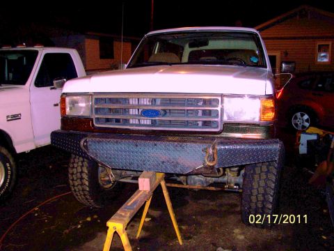1989 Ford Bronco - A white Ford truck is parked in front of a house, supported by yellow jack stands.