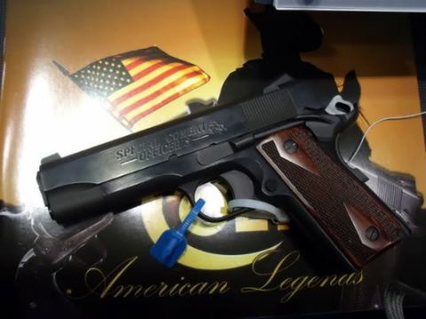 1995 Mercury Grand Marquis - A pistol with "Special Combat Officers" engraved on the slide rests on a display an American flag and "American Legends" text.