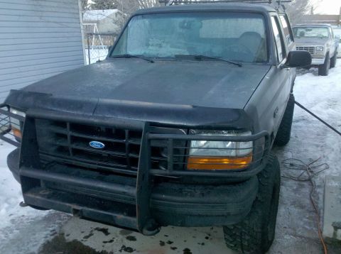 1995 Ford Bronco - Two Ford Broncos are parked outside in a snowy area, one in front of the other.