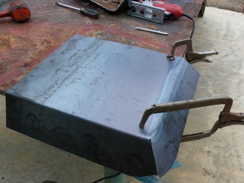 1976 Chevrolet Corvette - A metal part is being worked on with clamps and tools, including a jigsaw, on a workbench.