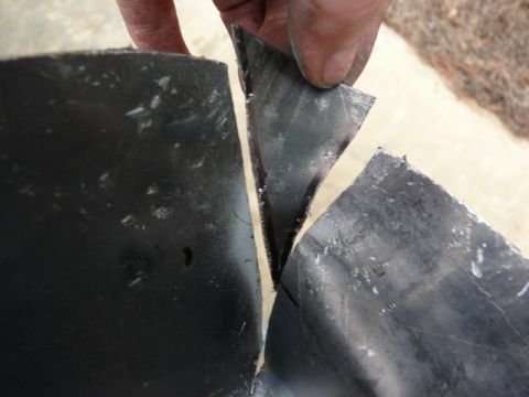 1976 Chevrolet Corvette - A hand is shown cutting a dark, textured metal part with a sharp edge.