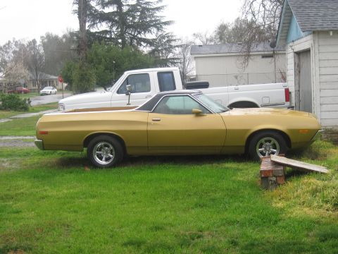 1972 Ford Ranchero - A gold 1972 Ford Ranchero is parked in a grassy yard next to a white pickup truck.