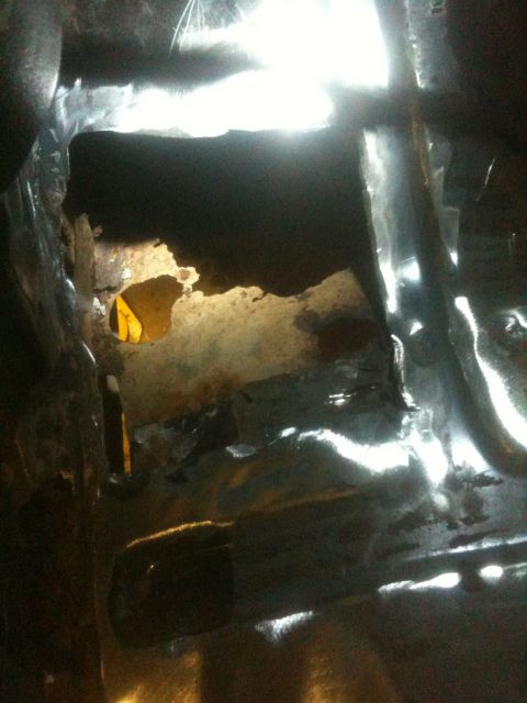 1993 Ford Bronco - The interior of a vehicle shows significant rust damage and a hole in the floor.