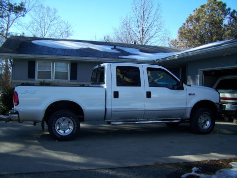 1989 Ford Bronco - A white Ford F-250 Super Duty pickup truck is parked in front of a house with snow on the roof.