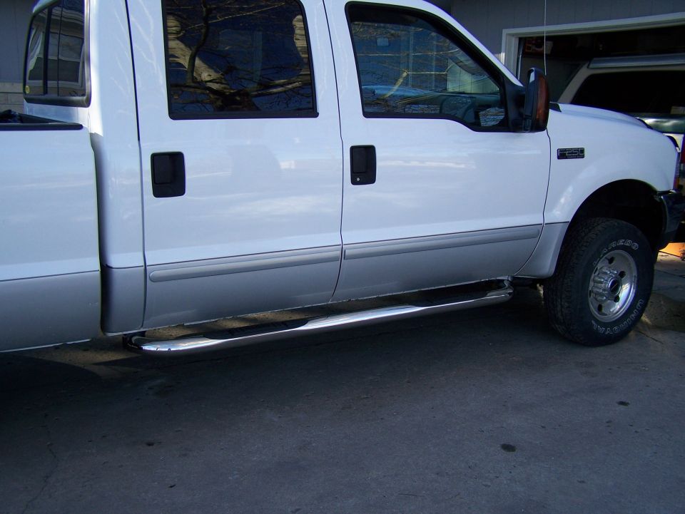 White pickup truck side view, showing two doors, chrome step bars, and a two-tone paint job