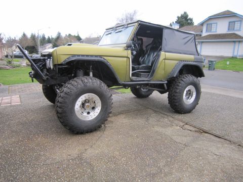 1996 Ford Bronco - This heavily modified SUV features oversized tires, a custom front bumper, and an open driver's door, suggesting off-road capabilities.