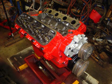 1989 Ford Bronco - A red V8 engine block is shown with its internal components visible, resting on a stand in a workshop.