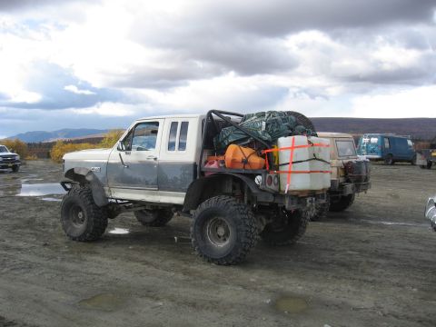 1990 Ford F-250 - Modified 1990 Ford F-250 pickup truck loaded with gear, parked outdoors with other vehicles under a cloudy sky.