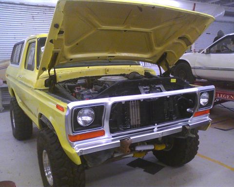 1978 Ford Bronco - A yellow 1978 Ford Bronco is shown with its hood open, revealing the engine bay.