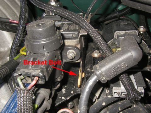1990 Ford Bronco - Close-up of an engine bay component, showing a black cylindrical solenoid with a red arrow and 'Bracket Bolt' text pointing to a brass-colo…