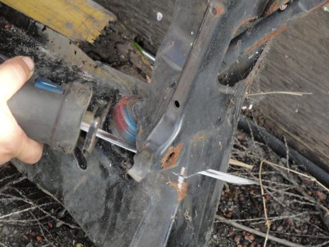 1995 Ford Taurus - A subframe part is being cut with a reciprocating saw, showing rust and wear.