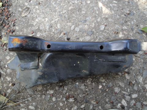 1995 Ford Taurus - A black metal subframe component lies on a gravel surface, showing signs of rust and wear.