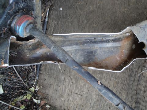 1995 Ford Taurus - A close-up view of a damaged automotive subframe component, showing rust and a metal rod.