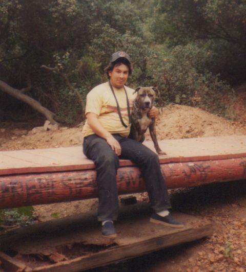 1968 Ford Mustang - A man and his dog pose for a photo while sitting on a rustic wooden beam outdoors.