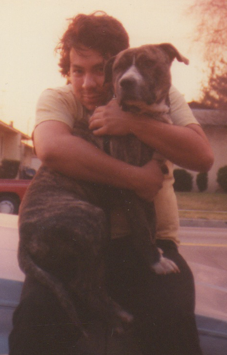 1968 Ford Mustang - A person embraces a brindle pit bull dog outdoors, with a red truck in the background.