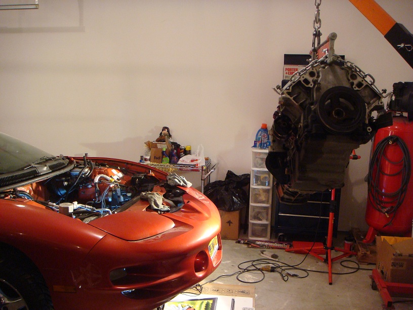 2001 Pontiac Trans Am with hood open, engine being lifted out by a hoist