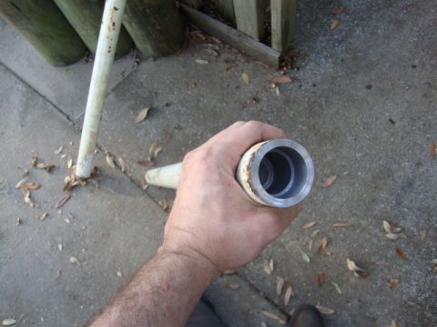 1986 Ford Bronco - A person holds a metal pipe with a sleeve, with wooden posts and concrete visible.