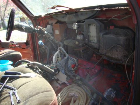 1986 Ford Bronco - The interior of a vehicle is shown with the dashboard disassembled, revealing wiring and mechanical parts.